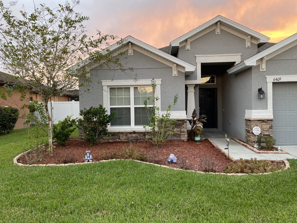 A house with a well-kept front yard and a paved driveway leading to the entrance.