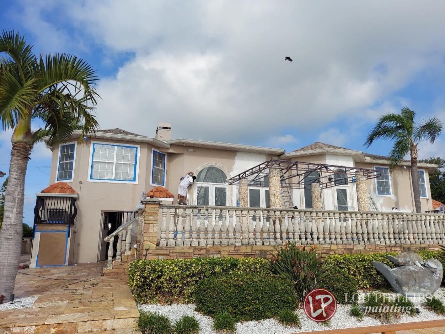 A house featuring a spacious patio surrounded by tall palm trees, creating a tropical outdoor setting.