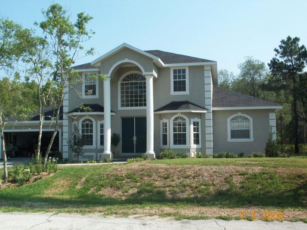 A large house with a spacious driveway and expansive front yard, showcasing a well-maintained landscape.