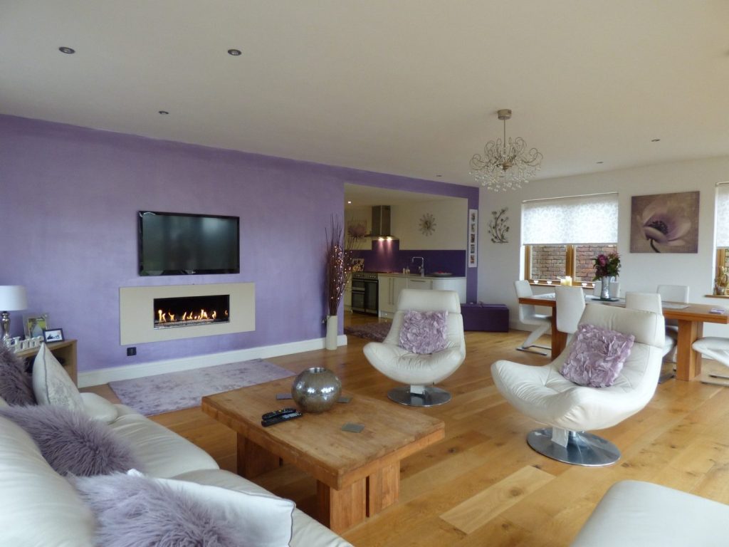 A living room featuring purple walls and stylish white furniture, creating a vibrant and modern atmosphere.